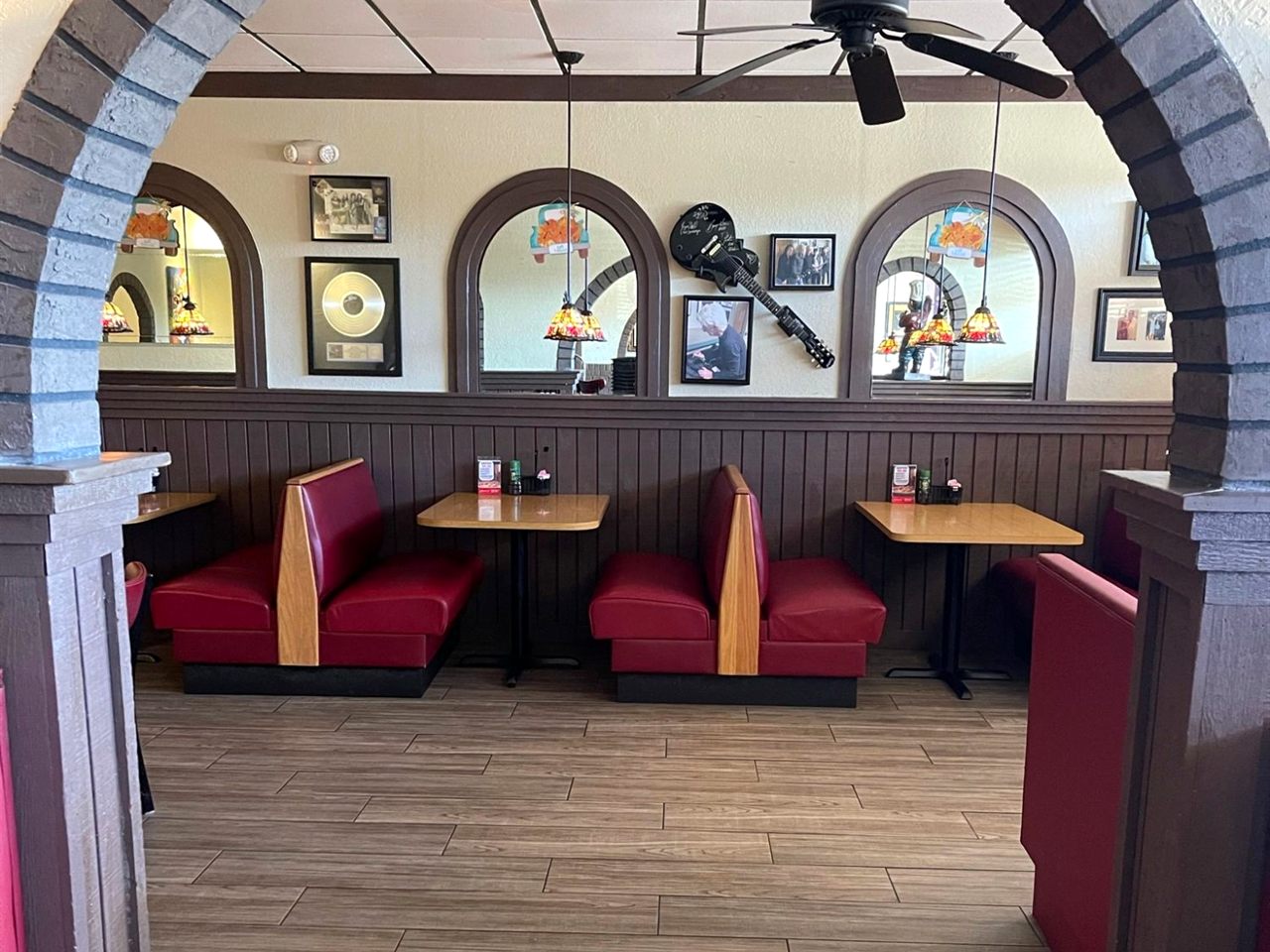 Red booths at Guido’s seen through a brick arch, with arched mirrors and music memorabilia